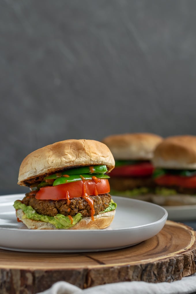 vegan curry seitan and black-eyed pea burgers with mashed avocado, sliced tomatoes, jalapeños, and hot sauce