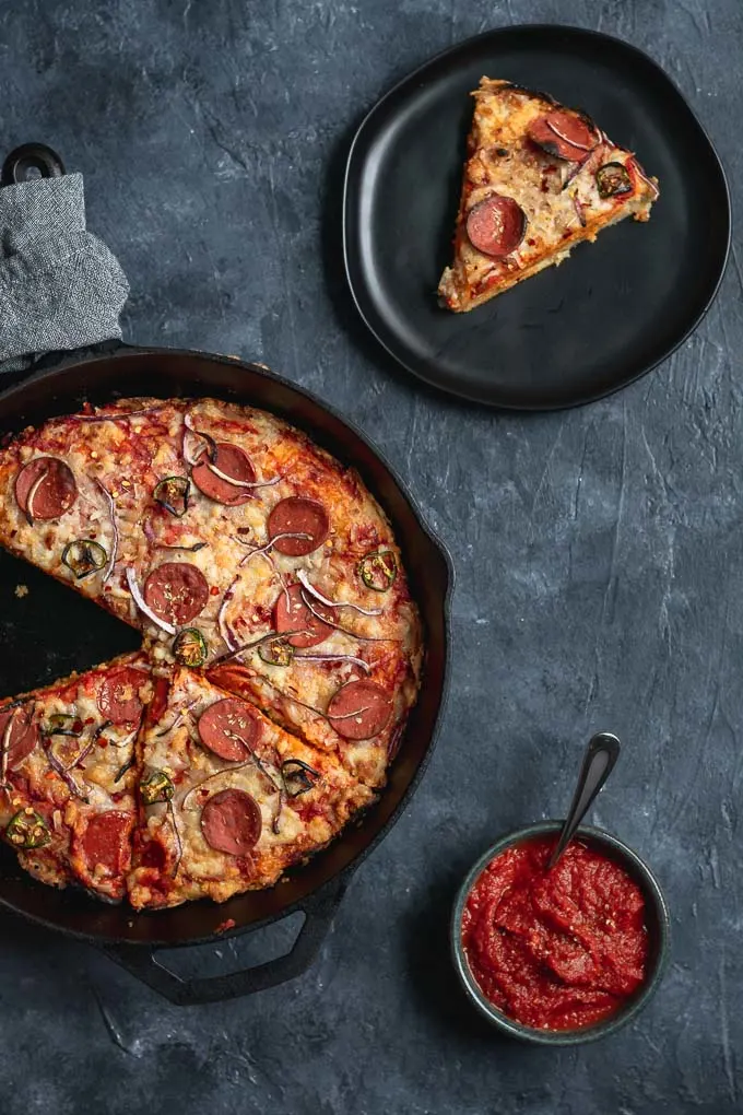 vegan pepperoni pan pizza in cast iron skillet one slice served on a plate