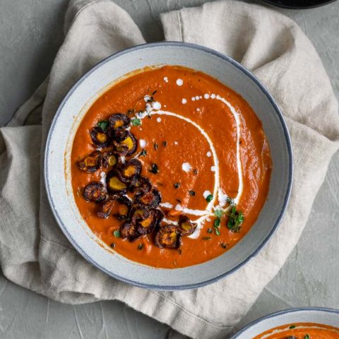 easy vegan roasted carrot soup with purple carrot chips and a drizzle of coconut milk and garnish of fresh thyme served with sourdough toast