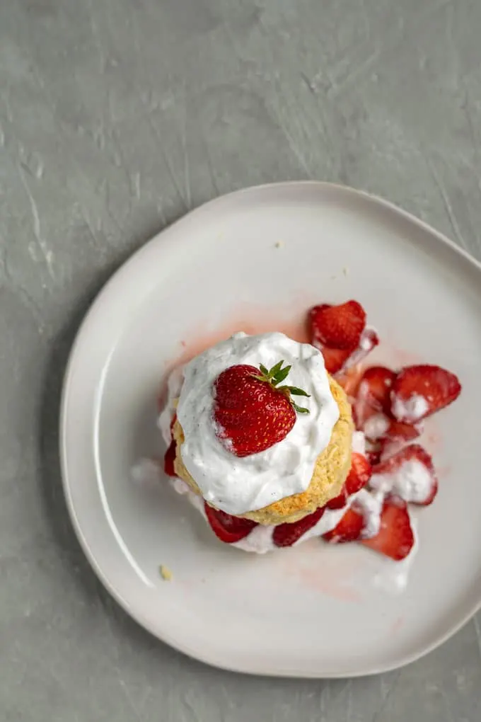 vegan strawberry shortcake with brandy soaked strawberries and vanilla bean whipped cream topped with a strawberry overhead view