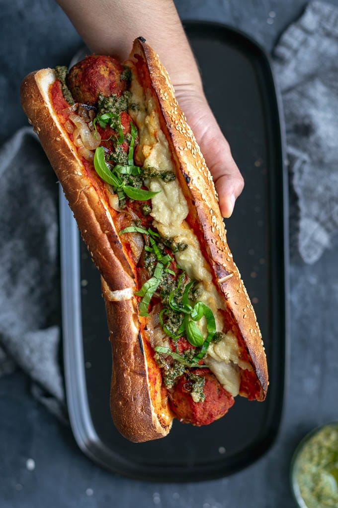 Vegan chickpea meatball subs with homemade mozzarella, pesto, and caramelized onions