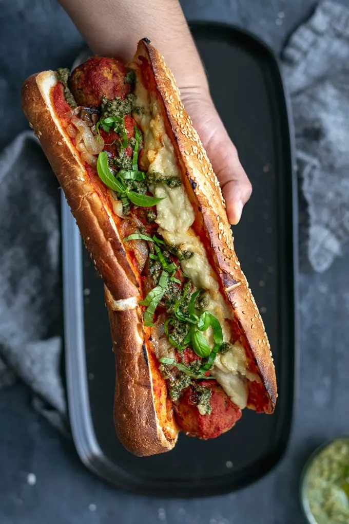 Vegan chickpea meatball subs with homemade mozzarella, pesto, and caramelized onions