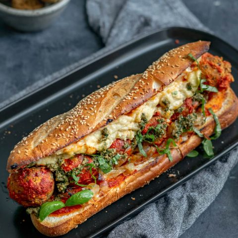 Vegan chickpea meatball subs with homemade mozzarella, pesto, and caramelized onions