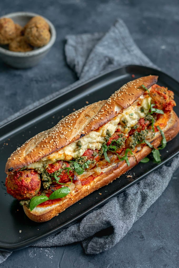 Vegan chickpea meatball subs with homemade mozzarella, pesto, and caramelized onions