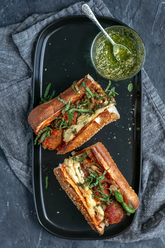 Vegan chickpea meatball subs with homemade mozzarella, pesto, and caramelized onions