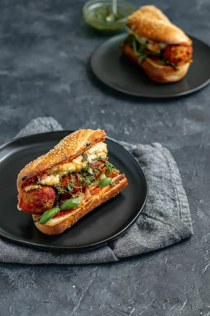 Vegan chickpea meatball subs with homemade mozzarella, pesto, and caramelized onions