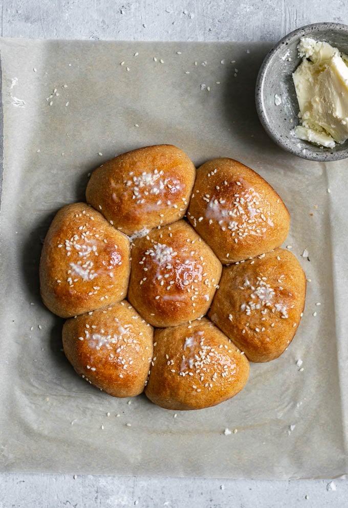 soft whole wheat dinner rolls baked in a round pan with vegan butter