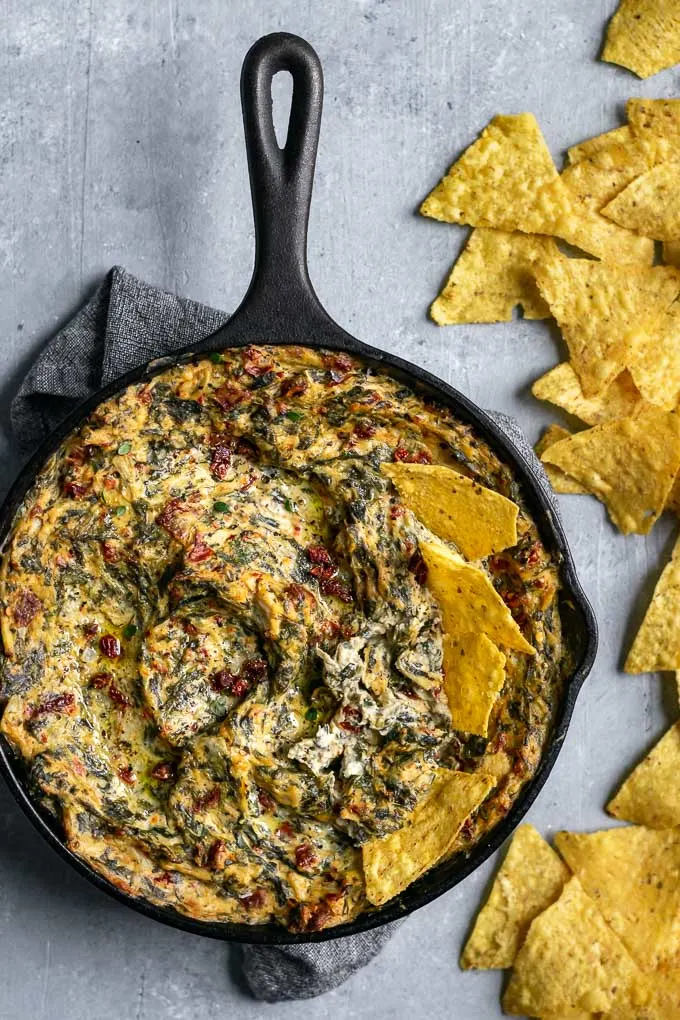 the best vegan spinach artichoke dip with tortilla chips in the skillet