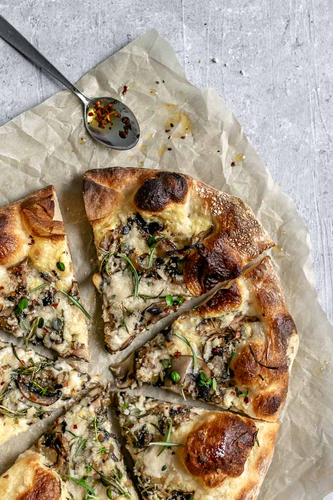 vegan caramelized mushroom pizza with garlic white sauce and fresh rosemary served with chili oil