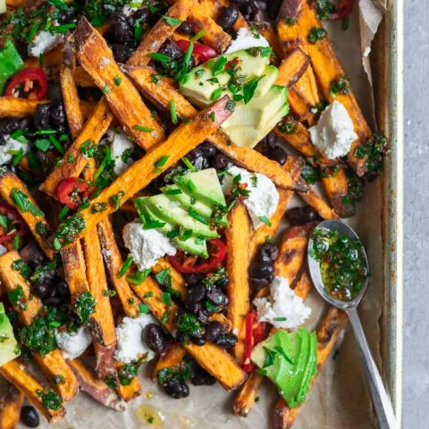 chimichurri loaded sweet potatoes with almond cheese, avocado, black beans, and sliced jalapeños