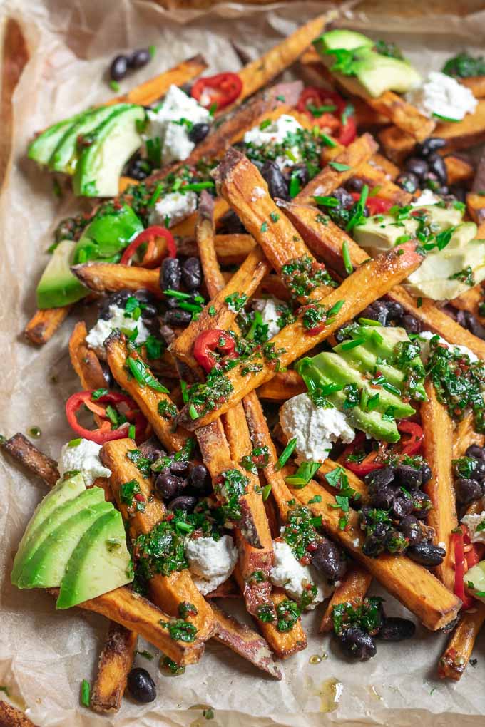 chimichurri loaded sweet potatoes with almond cheese, avocado, black beans, and sliced jalapeños