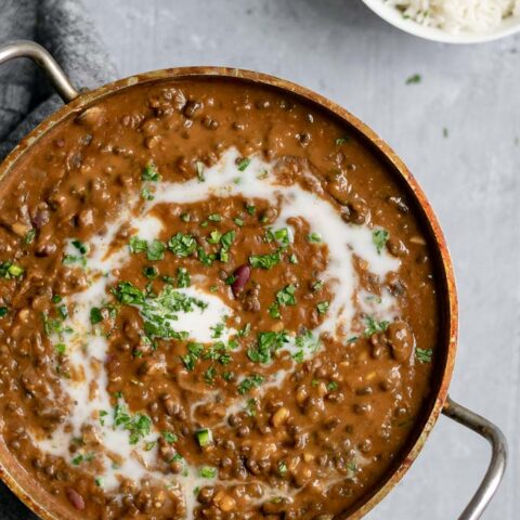 vegan dal makhani with a swirl of coconut milk and garnished with cilantro served with a bowl of basmati rice