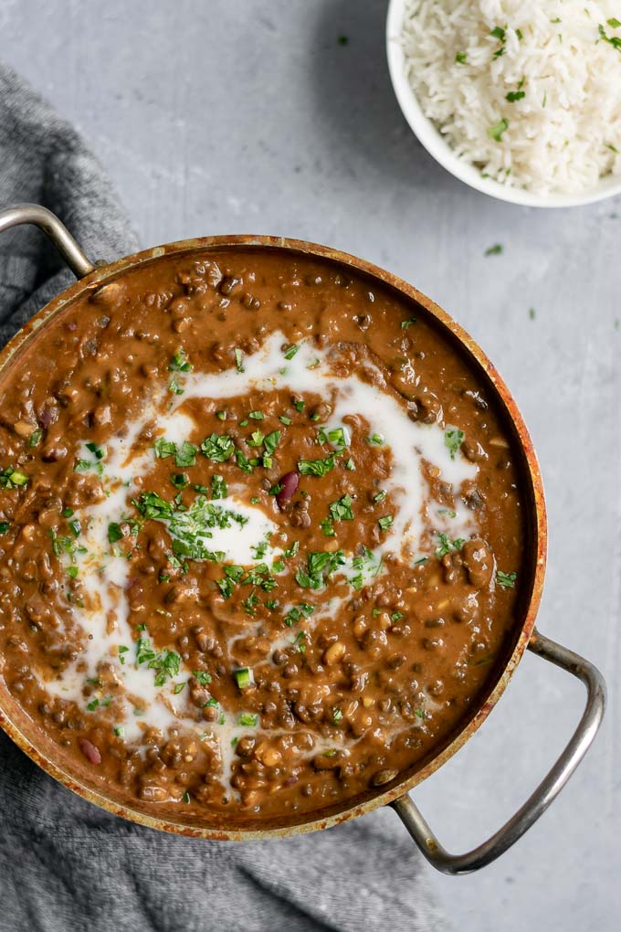vegan dal makhani with a swirl of coconut milk and garnished with cilantro served with a bowl of basmati rice