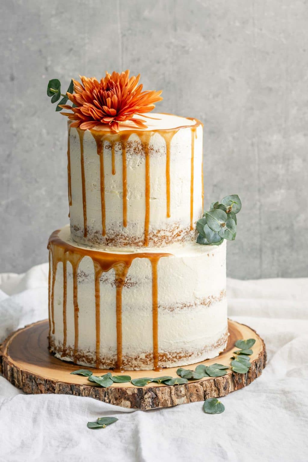 A 2-tier easy vegan vanilla cake decorated with flowers and a salted caramel drip