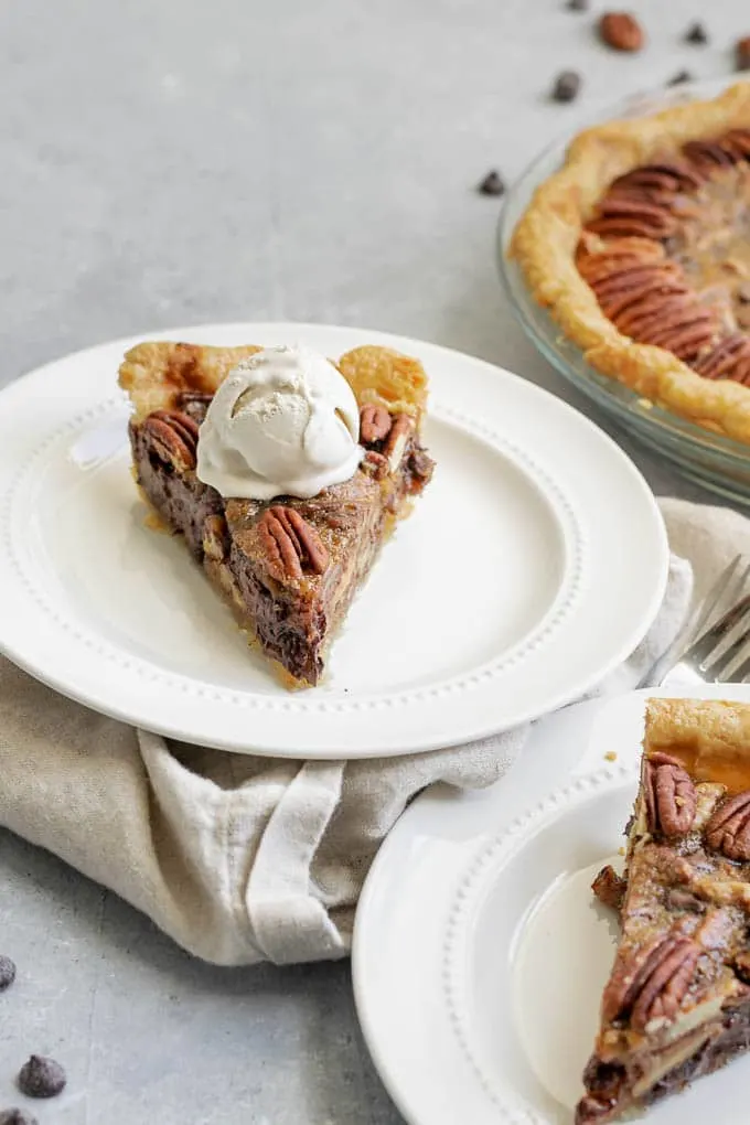 A slice of vegan chocolate bourbon pecan pie with a scoop of vanilla ice cream on top