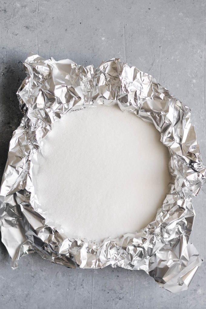 pie shell lined with aluminum foil and filled with sugar for blind baking