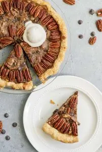 vegan chocolate bourbon pecan pie with a scoop of ice cream and two slices cut out, one on a plate
