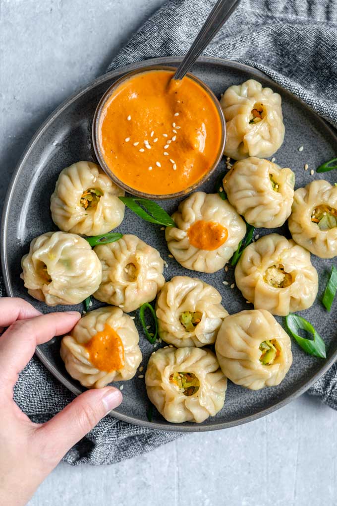 Picking up a Tibetan vegetable momo served with a spicy sesame chutney
