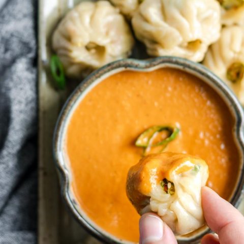 Tibetan vegetable momo dipped into spicy sesame tomato chutney