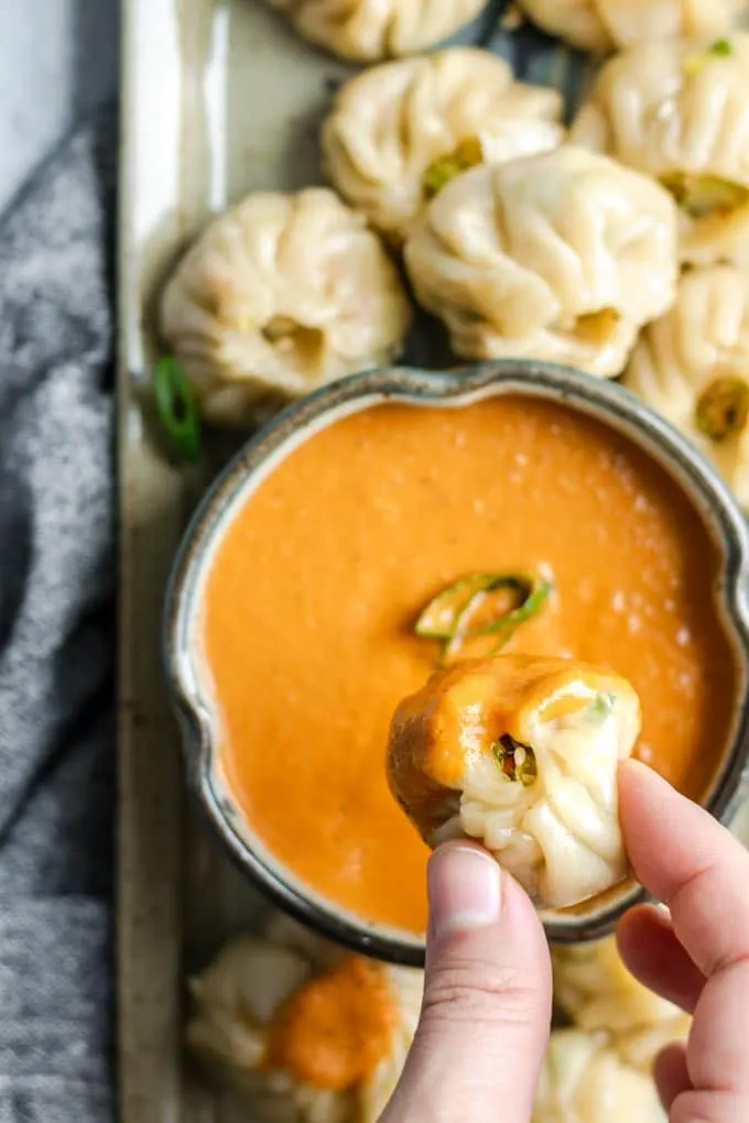 Tibetan vegetable momo dipped into spicy sesame tomato chutney