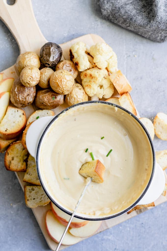 Dipping a piece of bread into vegan cheese fondue