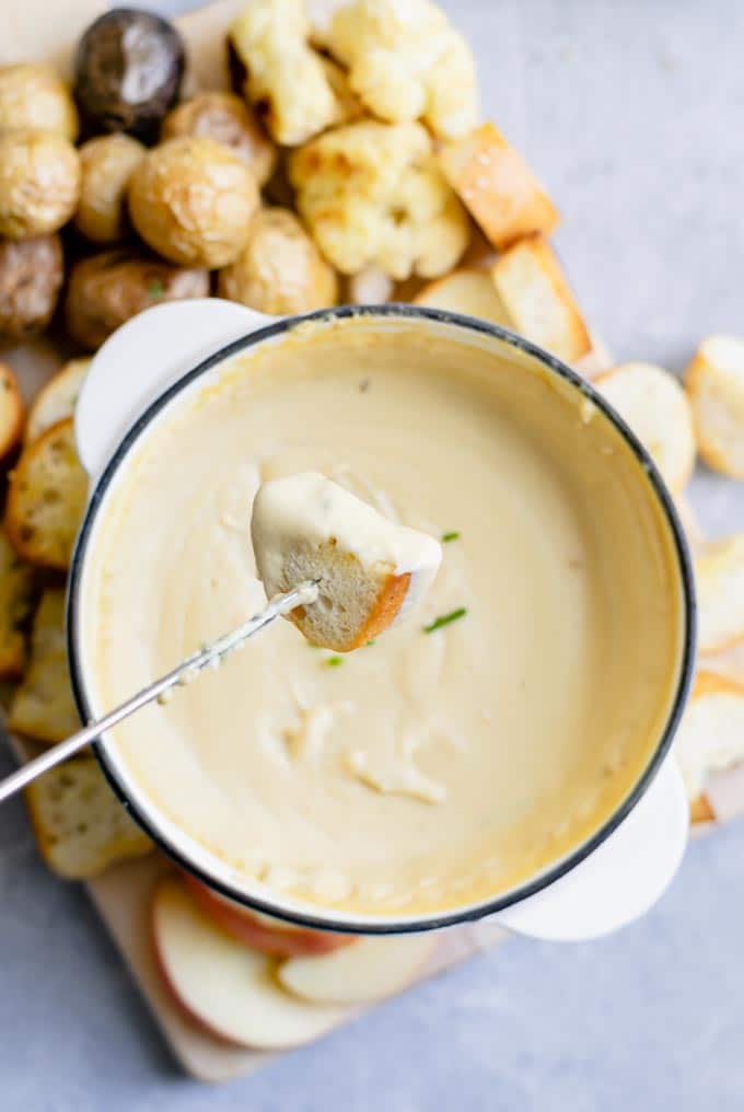 Dipping a piece of brea into the vegan cheese fondue