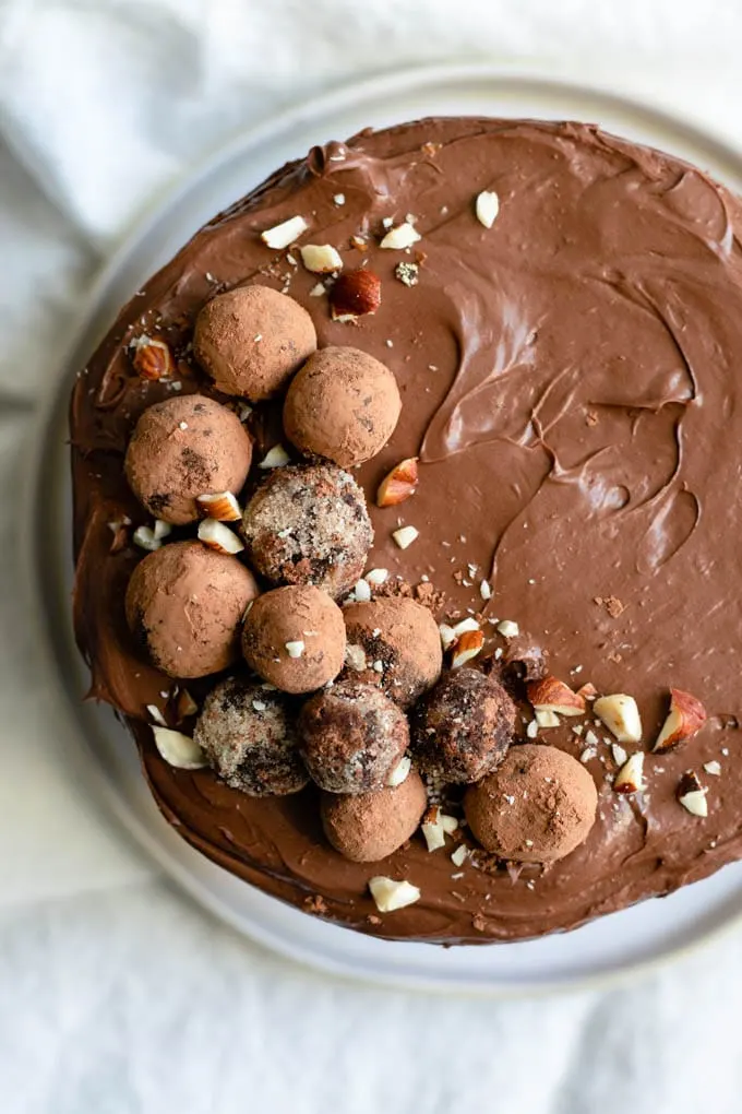 top view of vegan chocolate hazelnut cake frosted with whipped chocolate ganache and decorated with chocolate hazelnut truffles and chopped hazelnuts