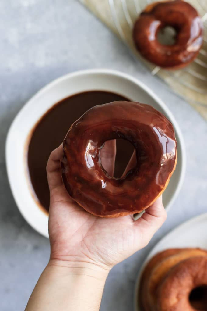 glazing vegan doughnuts with a chocolate glaze