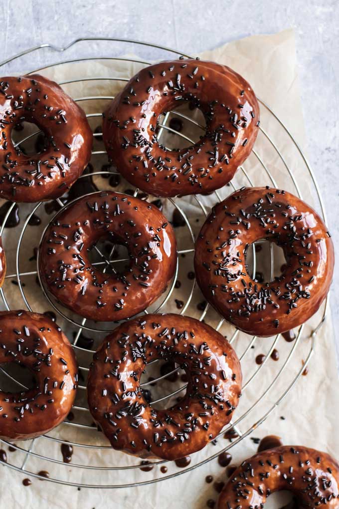 vegan chocolate glazed doughnuts topped with chocolate sprinkles