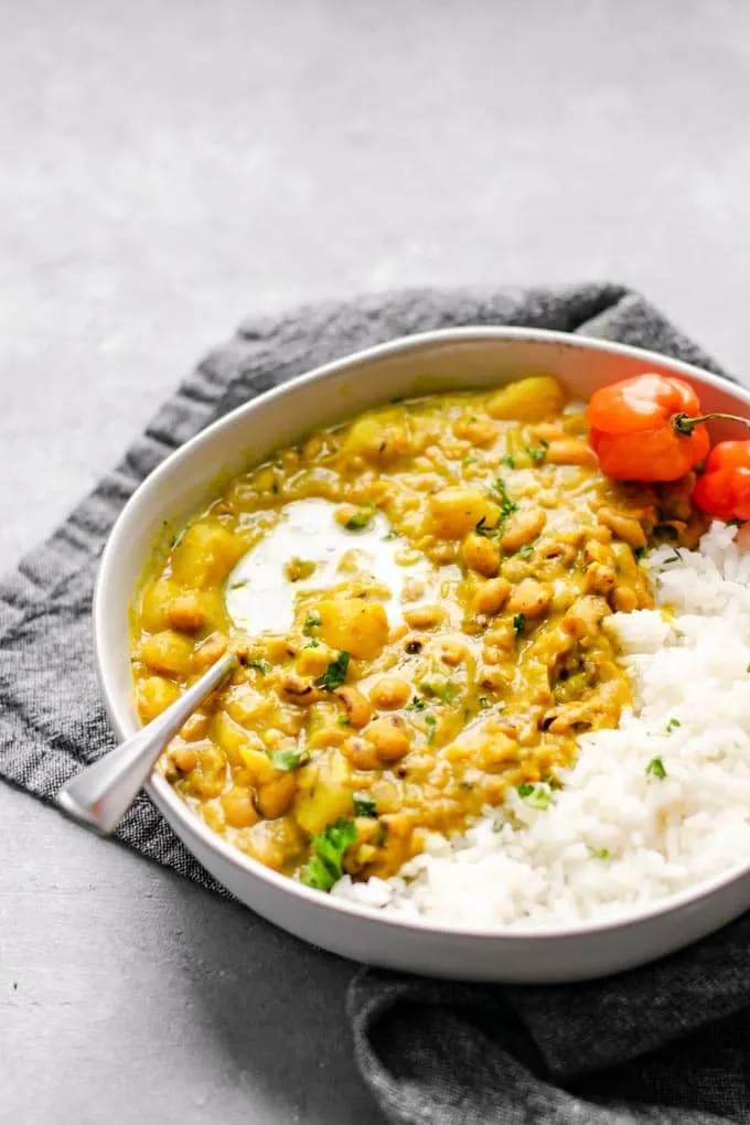 Jamaican black-eyed pea curry with rice and habanero peppers and a garnish of coconut milk and parsley angled view