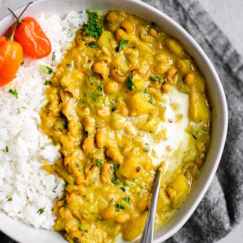 Jamaican black-eyed pea curry with rice and habanero peppers and a garnish of coconut milk and parsley overhead view