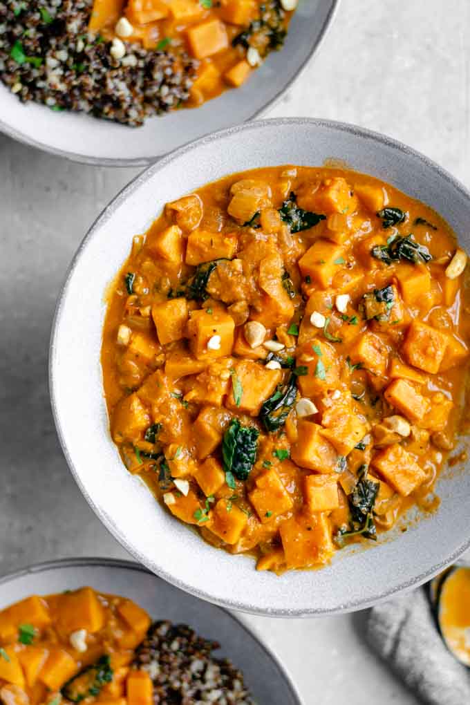 West African curry sweet potato, kale, and peanut stew garnished with cilantro and chopped peanuts