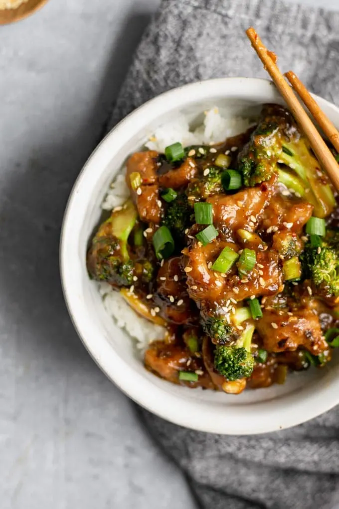 crispy orange seitan and broccoli with jasmine rice, with sticky chopsticks resting on bowl