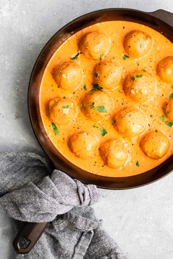 vegan chickpea meatballs in roasted red pepper sauce, cooked in a cast iron skillet