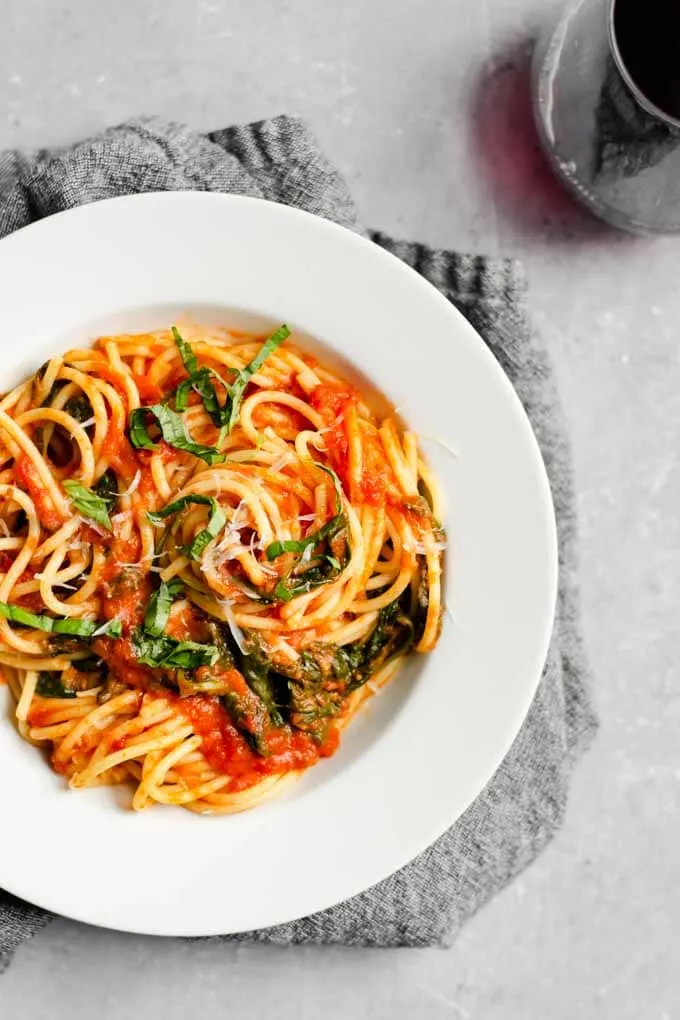 spaghetti with classic homemade marinara with spinach and a glass of red wine