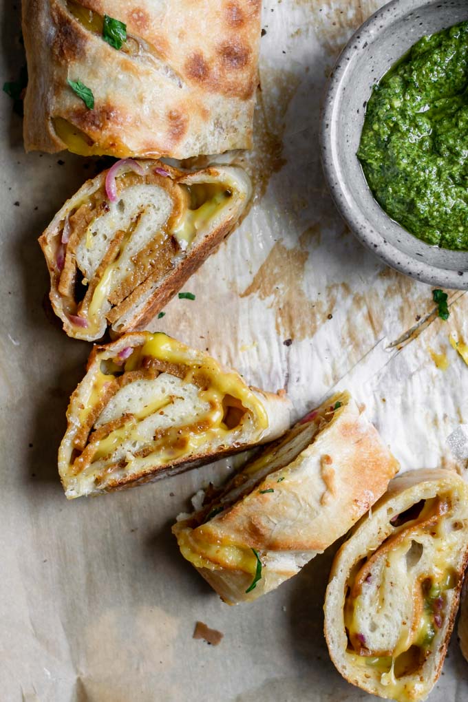 vegan stromboli sliced on baking tray served with pesto