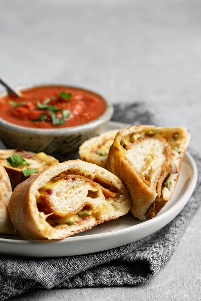 vegan stromboli, sliced and on a plate with marinara for dipping