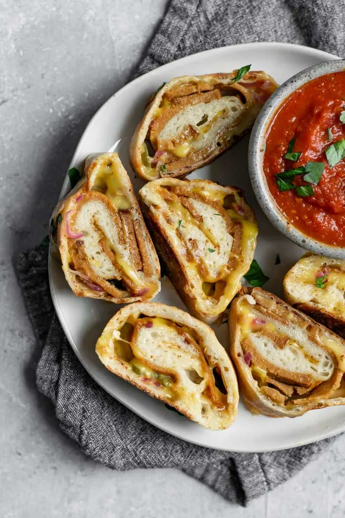 vegan stromboli, sliced and served on a plate with marinara for dipping