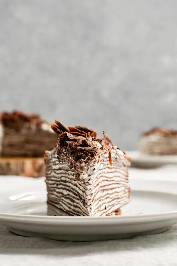 slice of vegan chocolate crepe cake with whipped cream filling