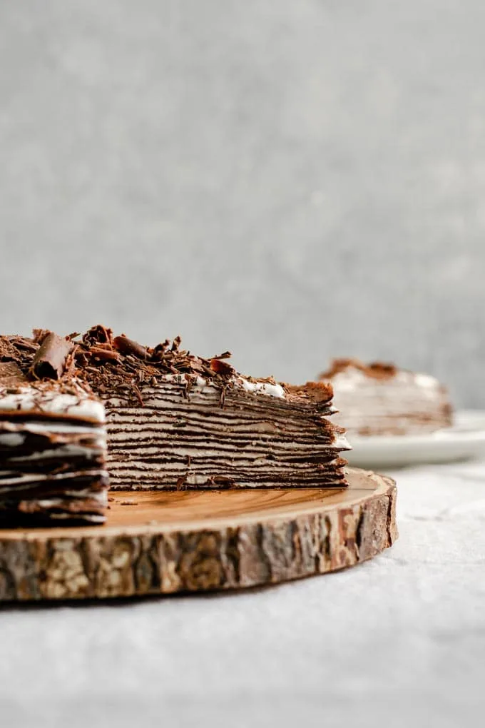 slices cut out of chocolate crepe cake with whipped cream filling to show layers