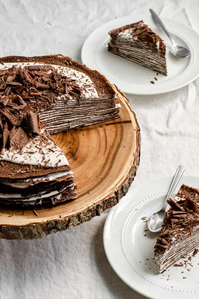 angled view of vegan dark chocolate crepe cake with whipped cream filling