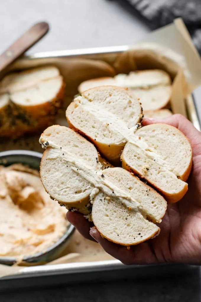 close up of a bagel filled with plain cultured cashew cream cheese and held up by hand