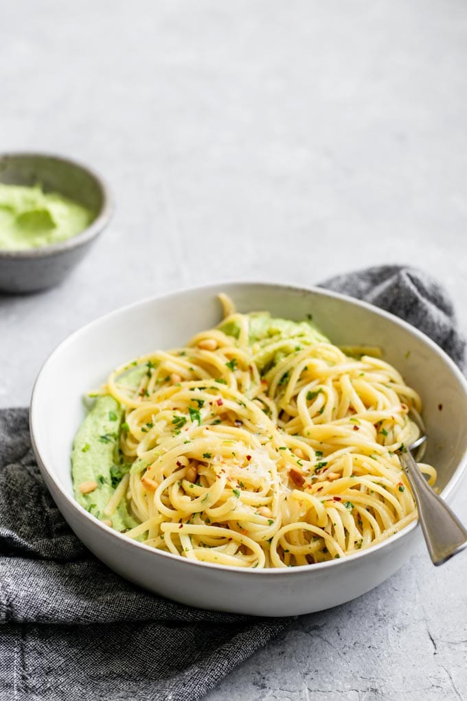 side view of the garlic linguine in a bowl over some vegan whipped pea ricotta, extra pea ricotta in a second bowl