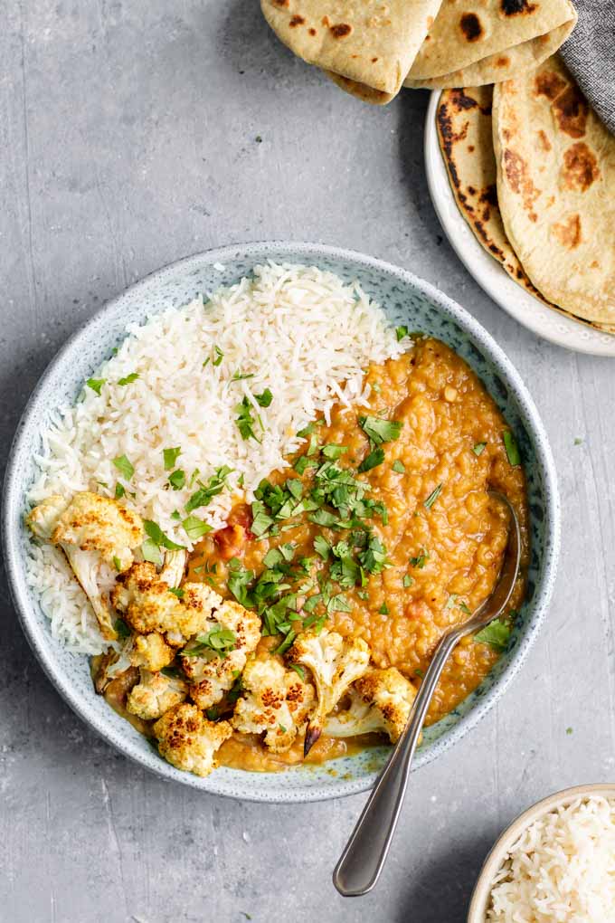 Masoor Tadka Dal wird in einer blauen Schüssel mit Chapati und extra Basmatireis serviert