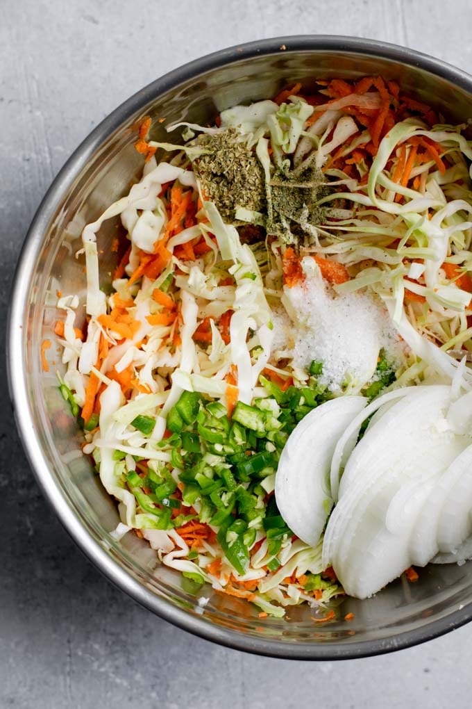 shredded cabbage, onion, carrots, jalapeño, oregano, and salt ready to be mixed together to make the curtido