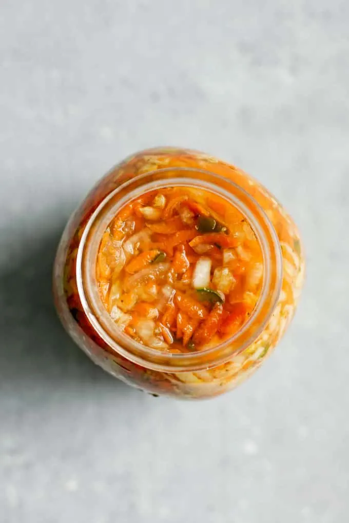 top view of Salvadoran curtido fermenting in a mason jar. Mostly carrots are seen from above.