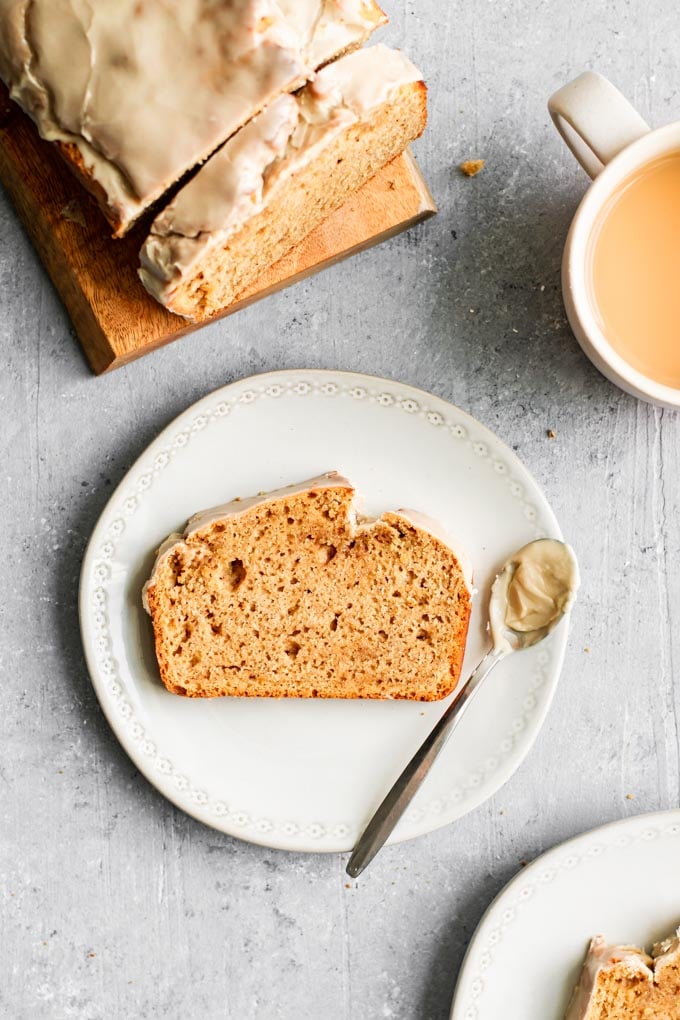 a slice of vegan chai spice loaf cake with a spoon of glaze on the plate