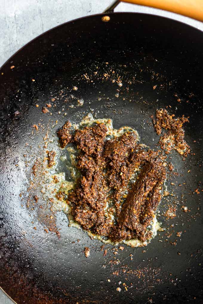 cooking the massaman curry paste in coconut cream in a wok until the oil splits from the curry paste