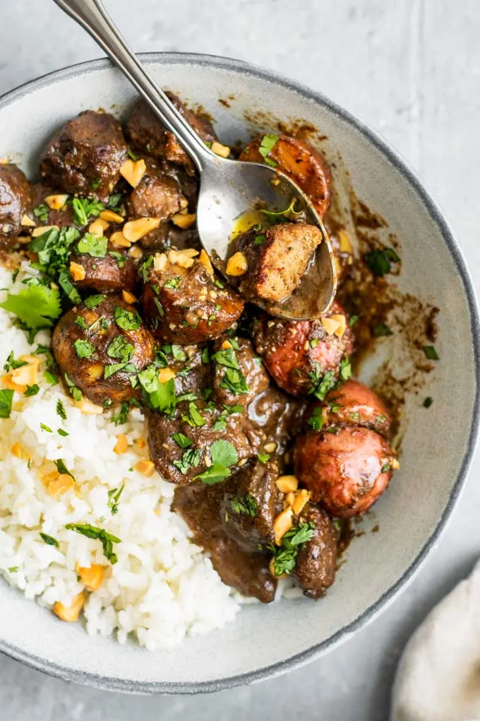 a piece of the vegan beef on a spoon in a bowl of the massaman curry