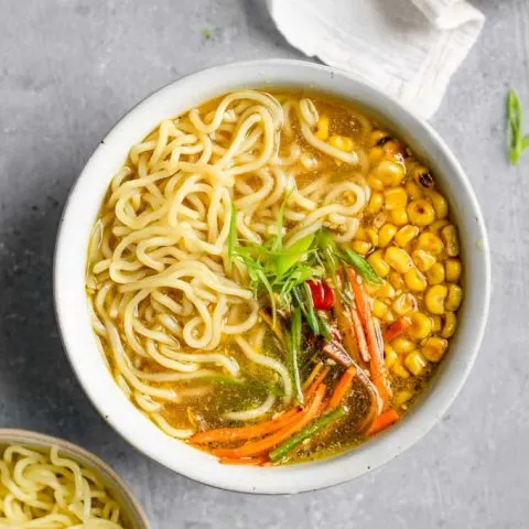 overhead shot of a bowl of vegan ramen with miso tahini broth and an extra bowl of ramen noodles on the side